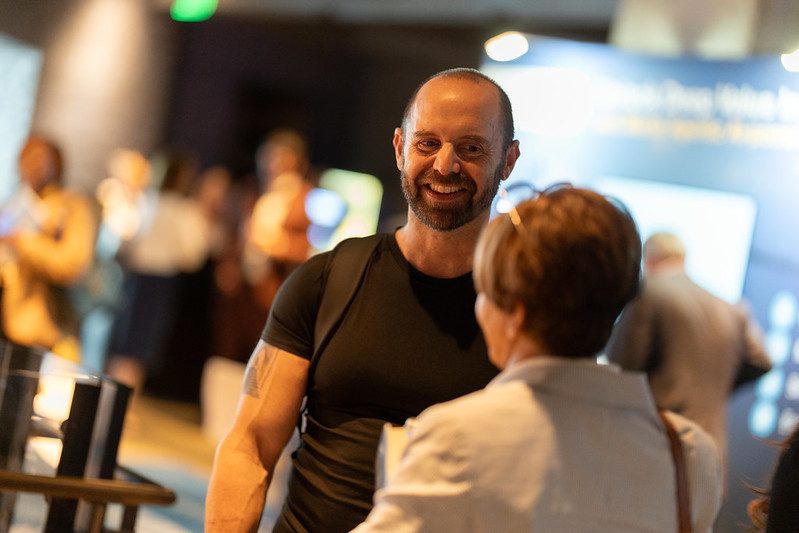 Todd Kashdan smiling in conversation with an attendee at an event
