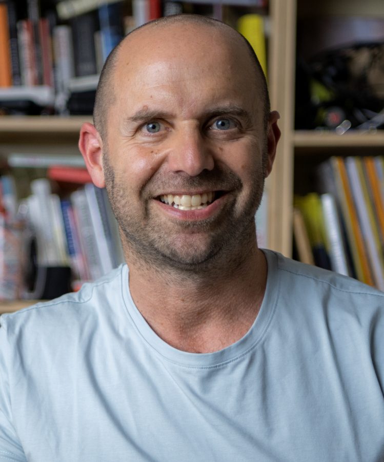 Headshot of Todd Kashdan smiling in front of bookshelves