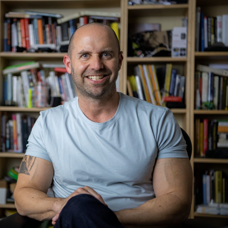 Todd Kashdan seated and smiling in his library