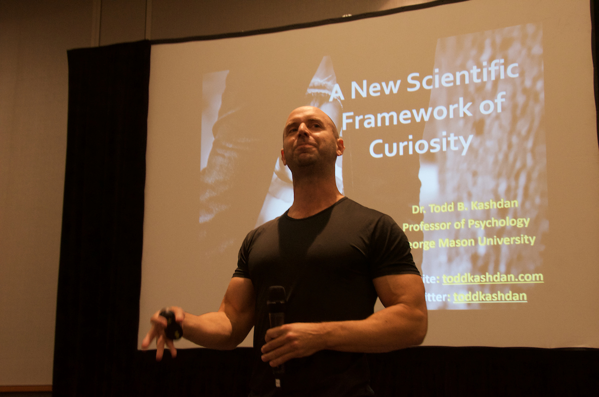 Todd Kashdan on stage below a slide reading A New Scientific Framework of Curiosity