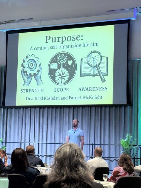 Todd Kashdan on stage below a large slide reading Purpose: A central, self-organizing life aim