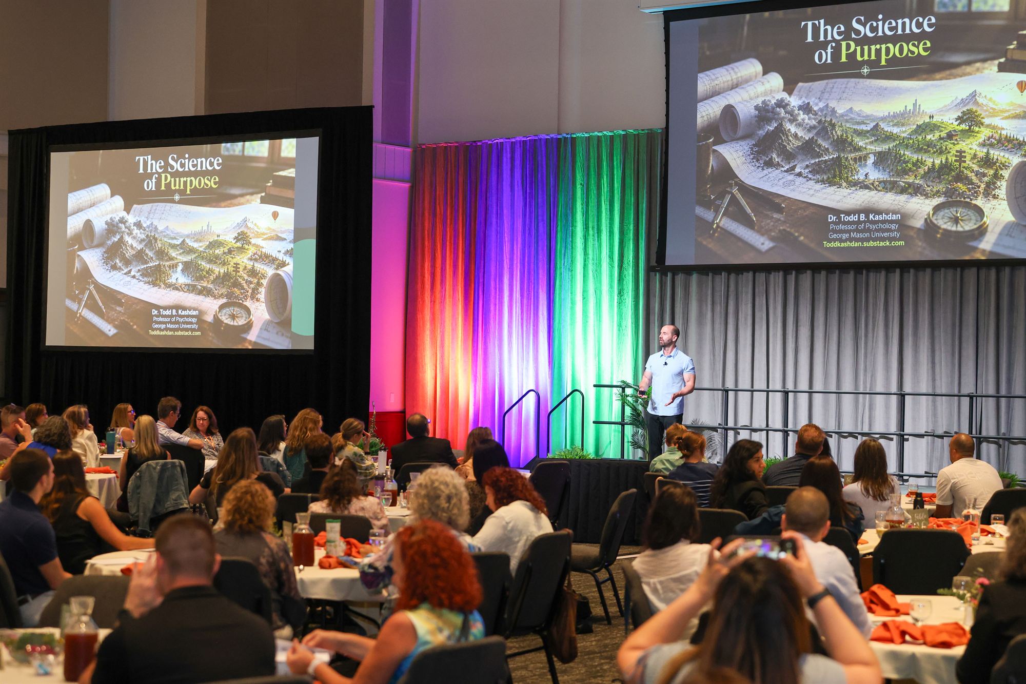Todd Kashdan presenting The Science of Purpose to a full banquet room, slides on two large screens