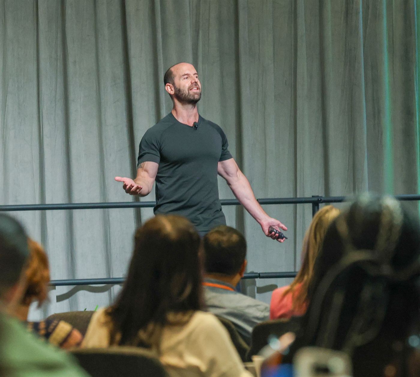 Todd Kashdan on stage, arms open, speaking to a seated audience