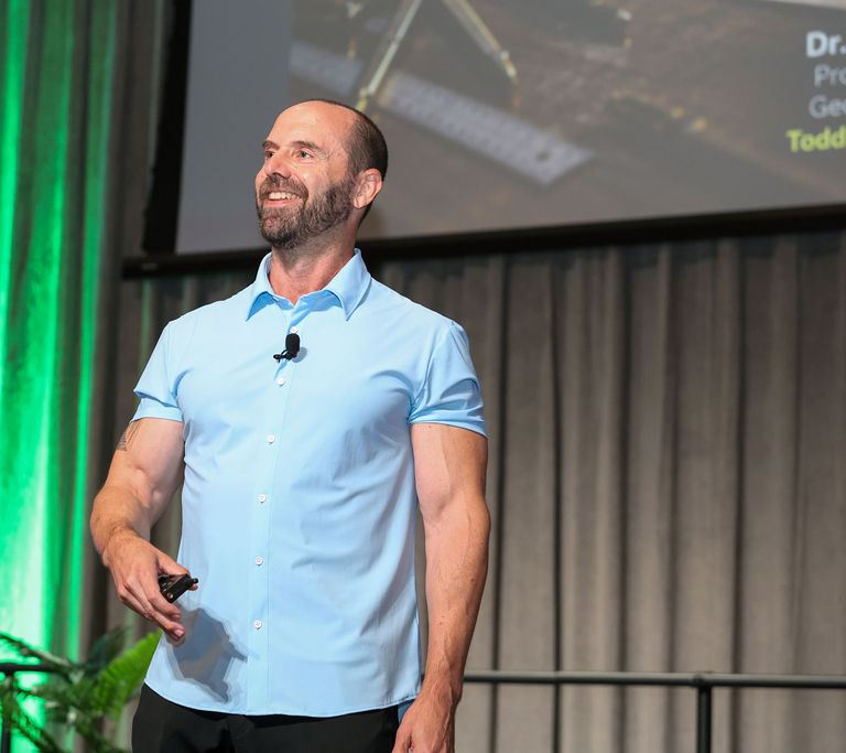 Todd Kashdan smiling on stage with a clicker in hand